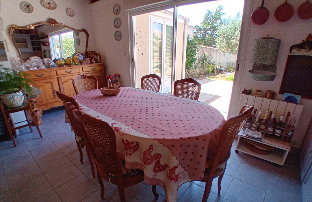 Salle à manger conviviale de La Roseraie avec grande table en bois et baie vitrée ouverte sur le jardin