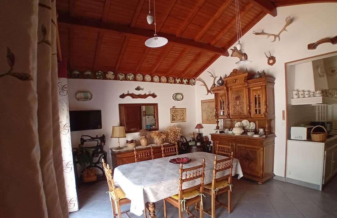 Salle à manger rustique avec poutres apparentes, cheminement typique et mobilier en bois dans un logement de La Roseraie