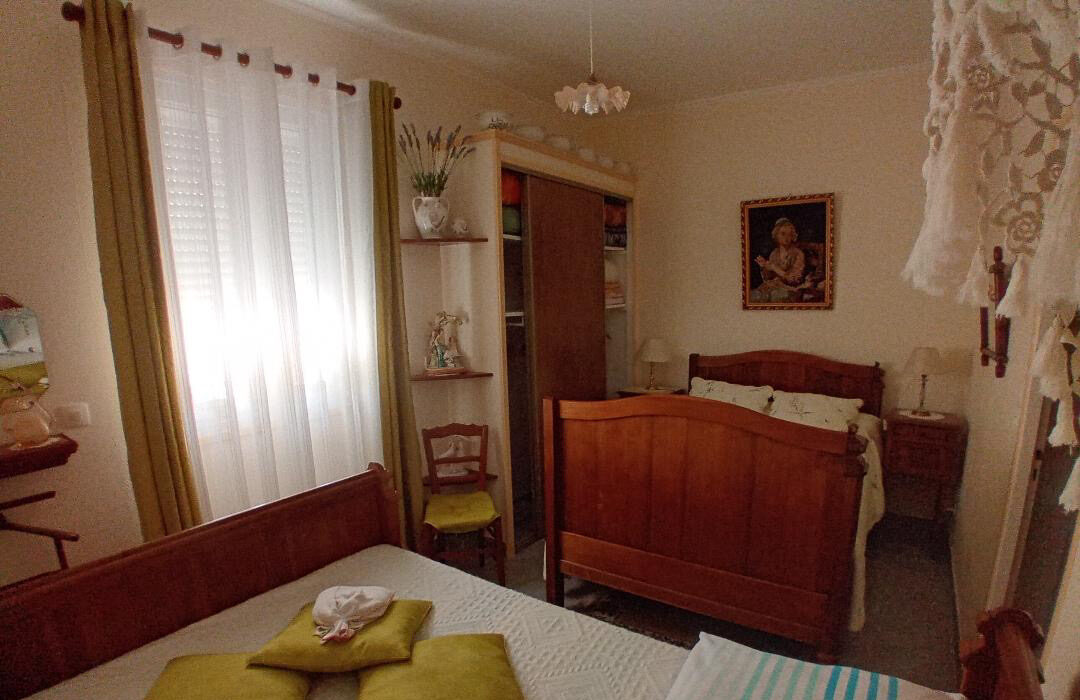 Chambre familiale avec deux lits jumeaux et mobilier en bois traditionnel dans un logement de La Roseraie