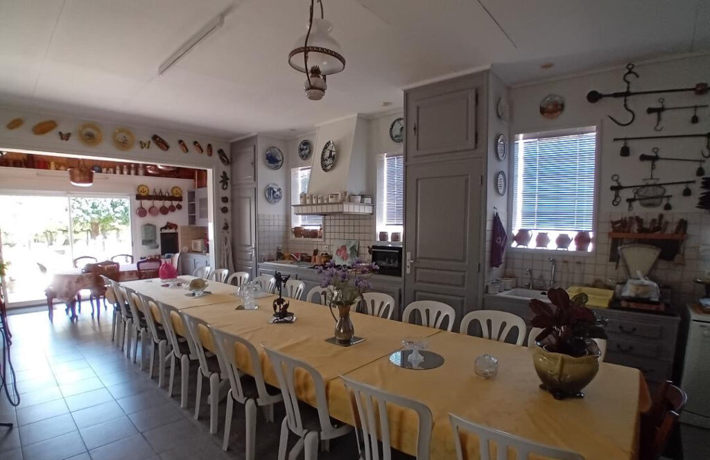 Grande cuisine équipée avec longue table conviviale pouvant accueillir un groupe à La Roseraie